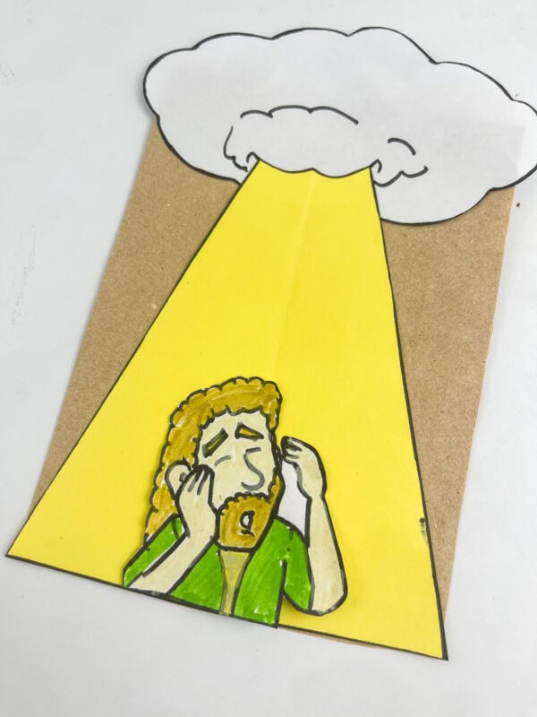A close-up view of the completed paper bag craft focusing on the Saul character inside the yellow beam of light.