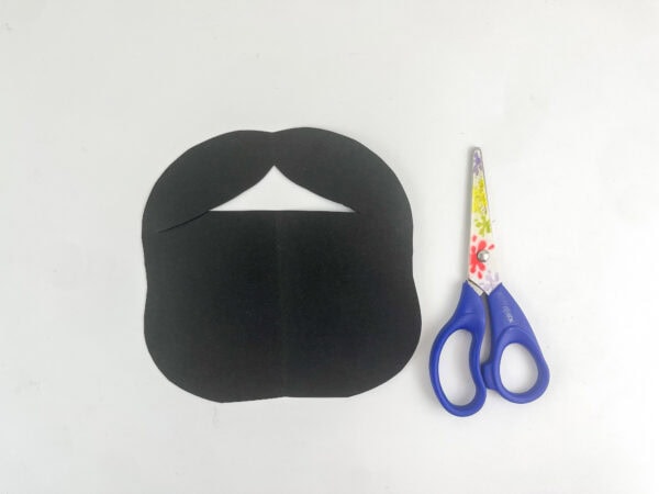 Black paper cut into a hair shape next to scissors