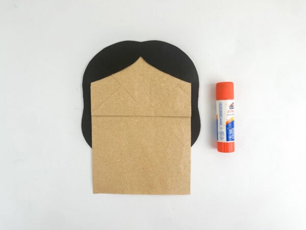 Black hair shape glued behind a brown paper bag