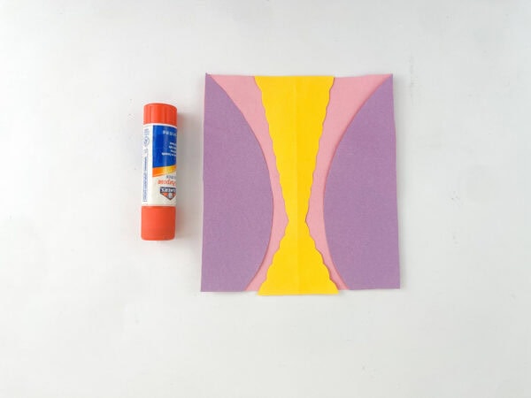  Purple, pink, and yellow paper pieces glued together to form a dress shape