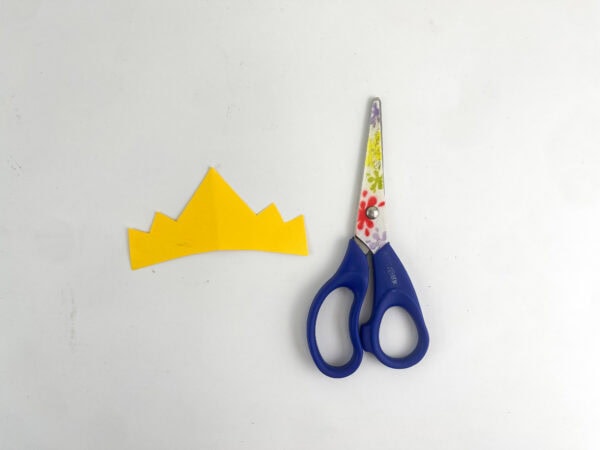 Yellow paper crown cut out next to scissors