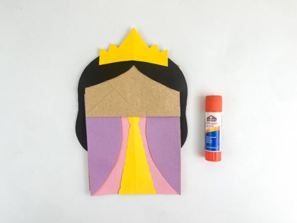 Paper bag craft with hair, dress, and yellow crown glued on, before facial features are added
