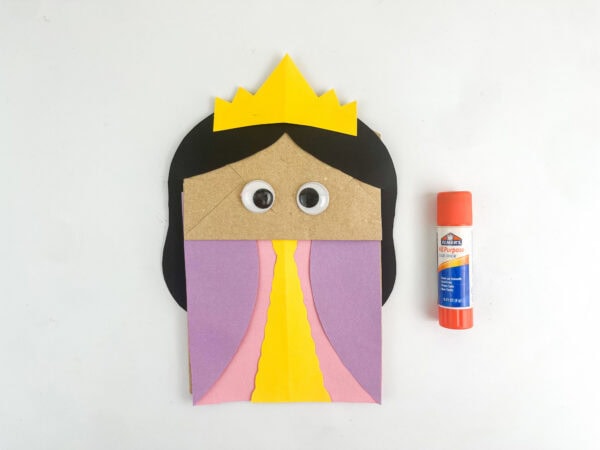 Paper bag craft with googly eyes added above the dress and crown