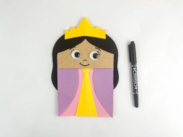  Paper bag craft with a smiling face and eyebrows drawn on, next to a marker