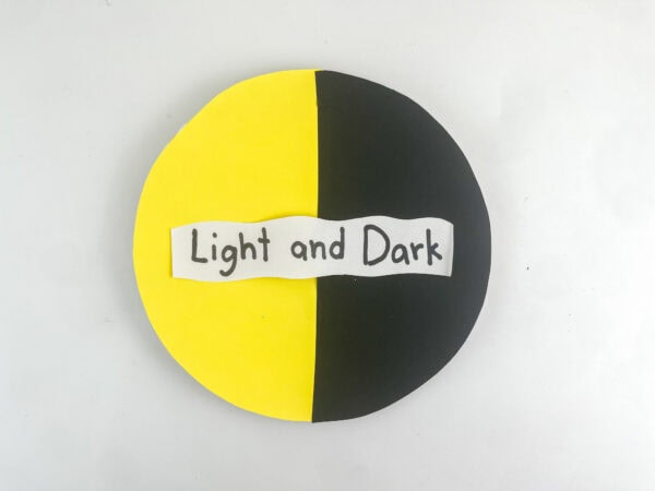 A finished yellow and black circle craft with the label "Light and Dark" centered on a plain white background.