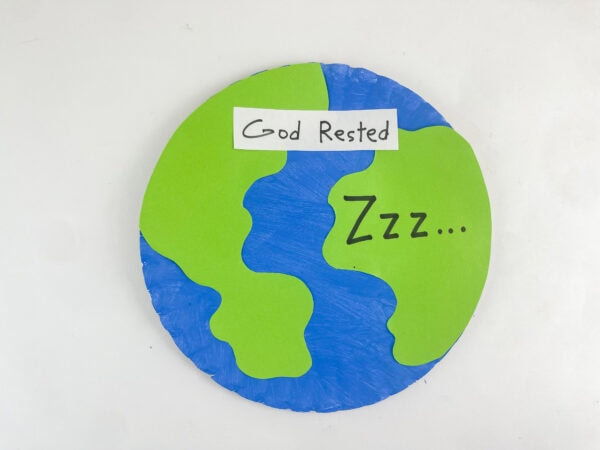 The finished paper plate Earth craft on a plain white background, showing the "God Rested" sign and "Zzz..." text.