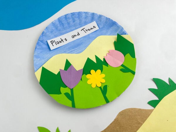 Angled overhead shot of the completed flower craft paper plate surrounded by decorative paper cutouts.