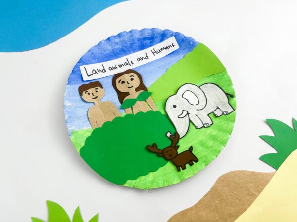 An angled top-down view of the finished paper plate craft resting on a background decorated with paper cutouts.