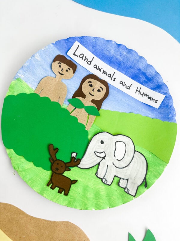 A close-up, top-down view focusing closely on the figures attached to the painted paper plate craft.