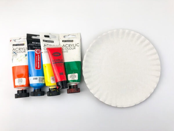  Four paint tubes (orange, blue, yellow, red) next to a plain white paper plate.