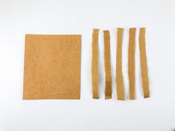 A square of brown cardboard next to five thin cardboard strips.
