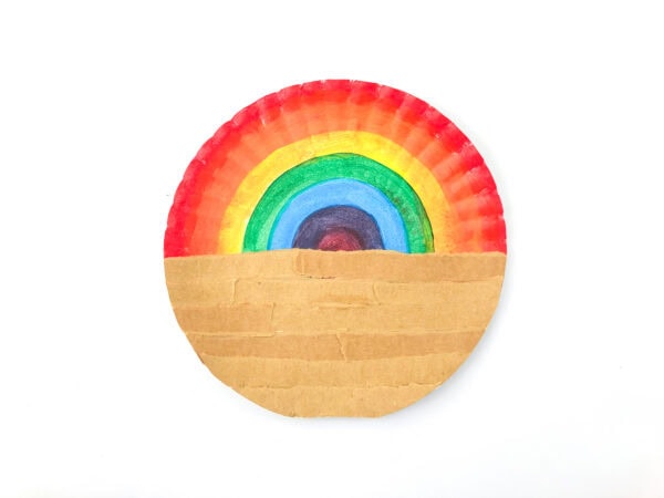 Rainbow paper plate with a strip of cardboard glued across the bottom half.