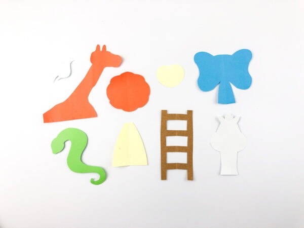Cut paper animal shapes: giraffe, elephant, snake, dove, lion mane, ladder, and lion body pieces.