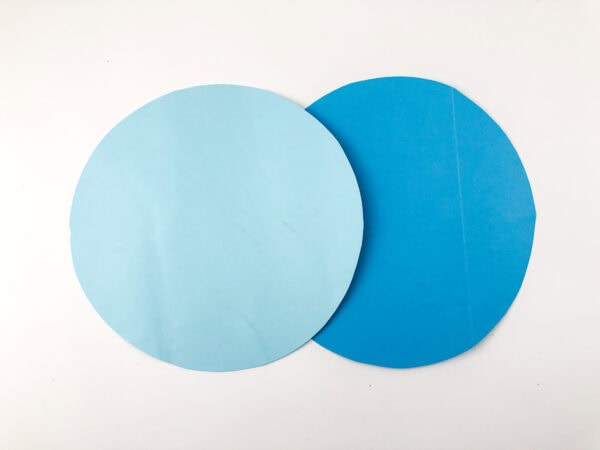 Two paper circles, one light blue and one darker blue, overlapping on a white background.