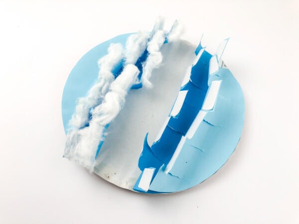The wave craft with cotton balls stretched into wisps and glued along one jagged blue edge.