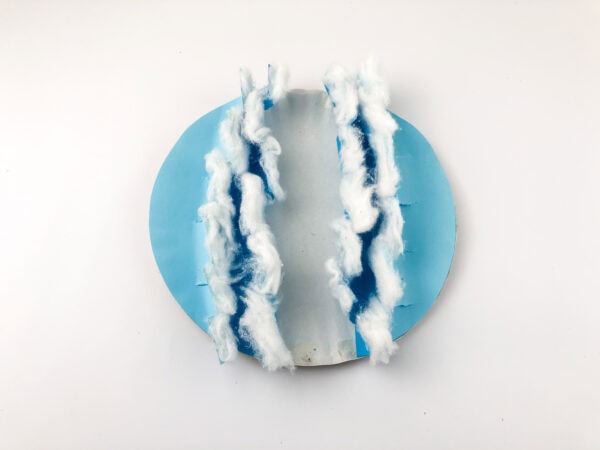 The circle craft with cotton wisps glued along both jagged blue edges, forming wave-like foam.