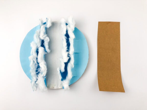 The cotton-trimmed wave craft next to a strip of brown paper.