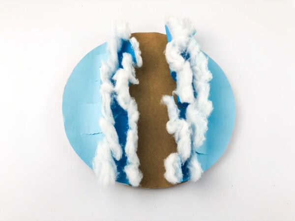 The brown paper strip glued down the center path between the cotton-trimmed blue waves.