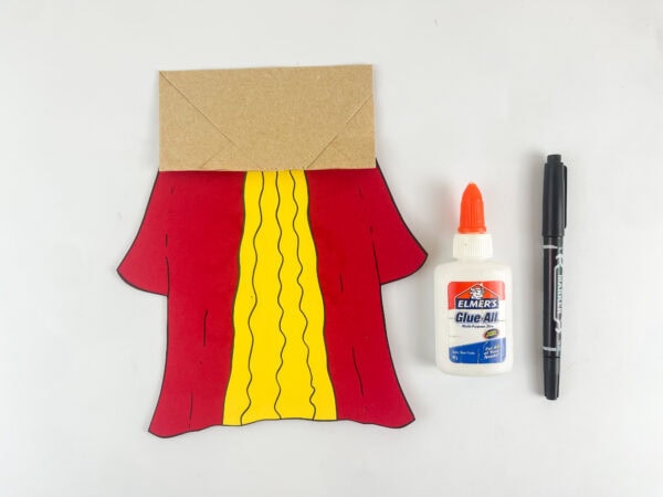 assembling King Solomon paper bag puppet body with red robe and yellow panel on kraft paper bag