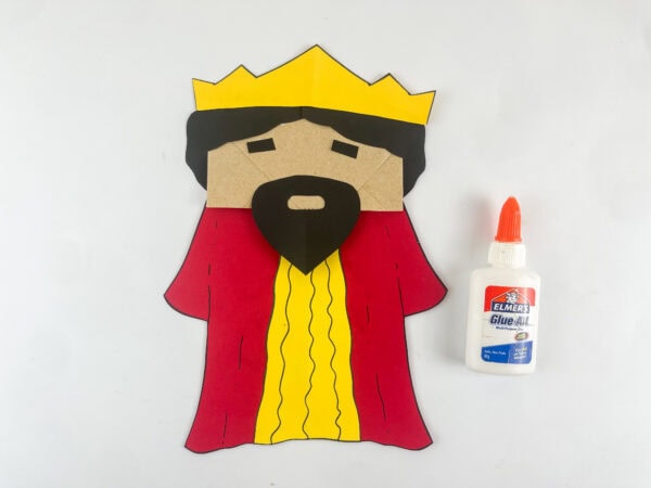 King Solomon paper bag puppet with black hair crown and beard assembled before adding googly eyes