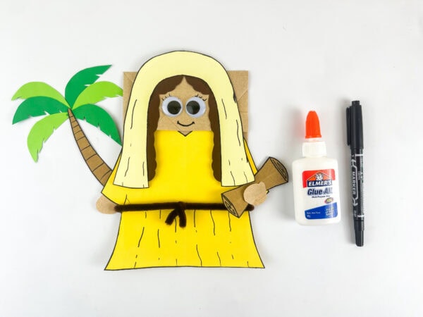 Deborah paper bag puppet with palm tree placed beside her and scroll in hand before adding googly eyes