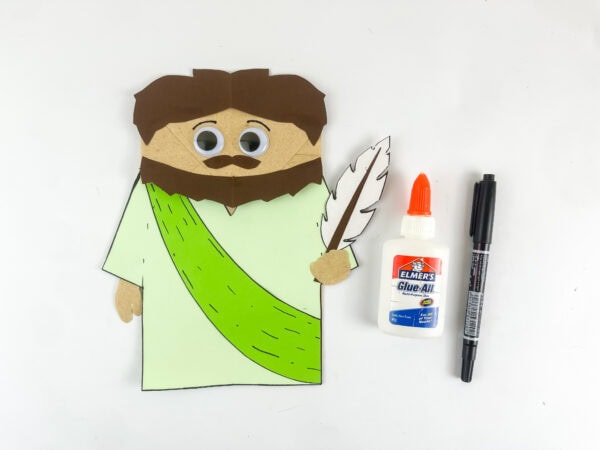 Completing an Isaiah paper bag puppet with googly eyes
