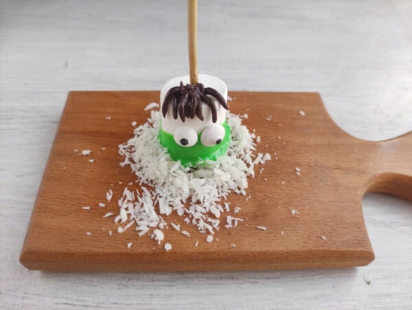 Green marshmallow monster dipped in coconut with chocolate hair.