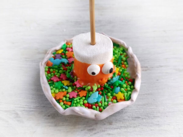Marshmallow monster dipped in orange coating and Halloween sprinkles.