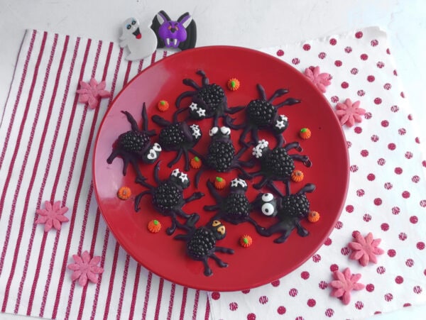 Blackberry Halloween spiders arranged on a red plate.