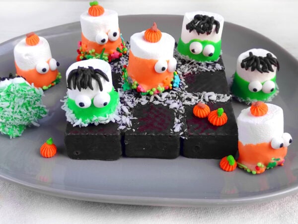 Halloween tic-tac-toe food game with marshmallow monsters and chocolate wafers.