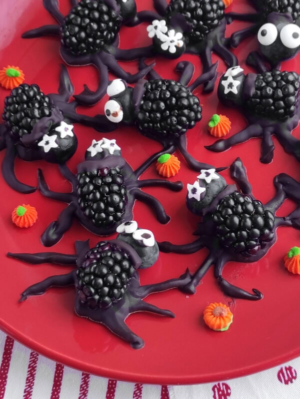 Blackberry Halloween spiders with candy eyes on a red plate