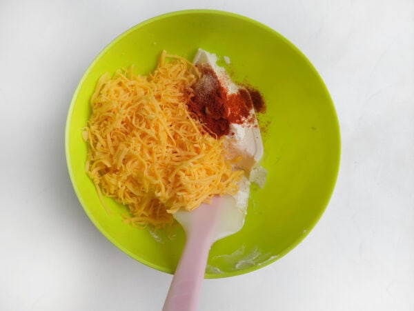 Cream cheese, shredded cheddar, smoked paprika, and garlic being mixed for a turkey cheese ball
