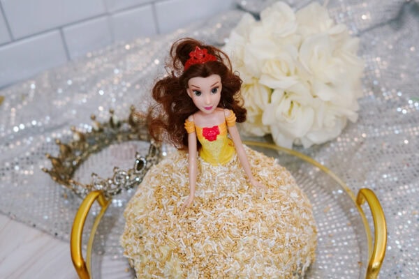 Belle doll placed in a sprinkle-covered gown cake