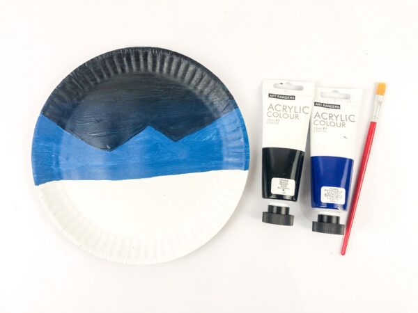 Paper plate painted half blue and half black with acrylic paints and brush.