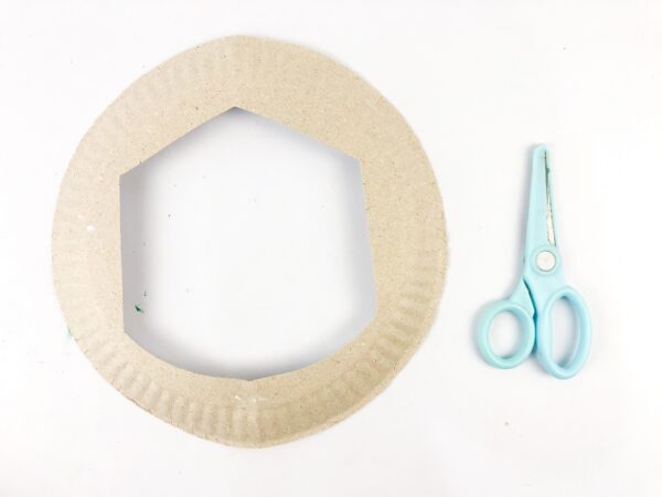 Paper plate with center cut out and scissors beside it.