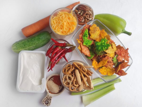 Ingredients for a turkey cheese ball including cream cheese, cheddar, vegetables, nuts, pretzels, and leaf chips