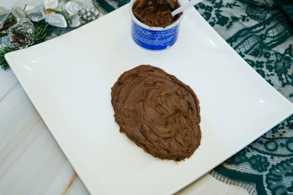 Chocolate frosting spread into an oval shape on a white square serving platter to form Rudolph's face.