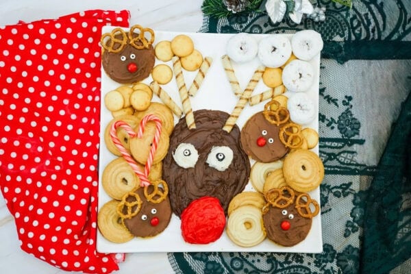 Overhead view of a Rudolph dessert board decorated with chocolate reindeer cookies, wafer antlers, candy canes, and assorted dippers.