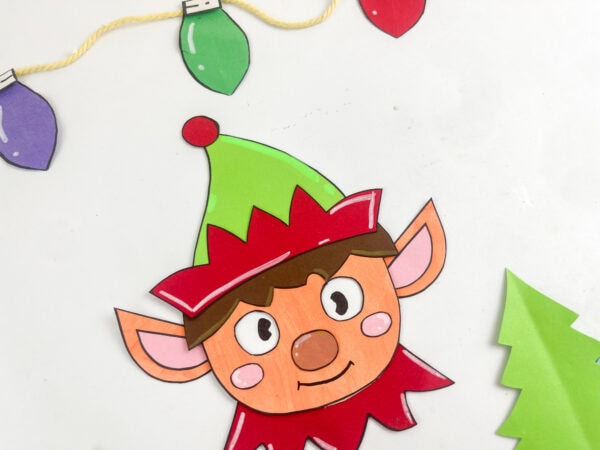 Paper elf with moving eyes, pointed ears, a green hat, and a red collar.