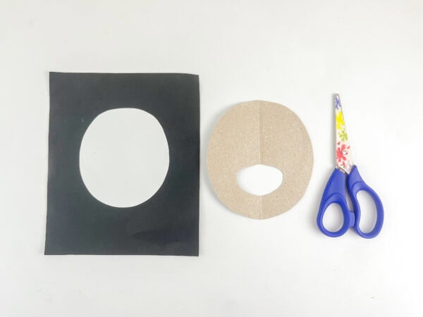 Oval cardboard backing with a finger hole beside the white moving eye insert.