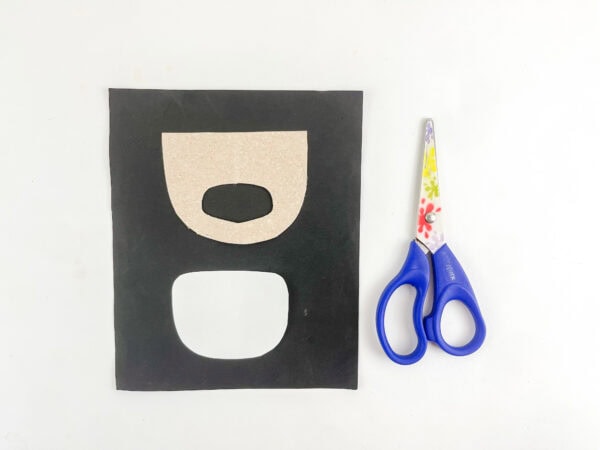 Cardboard elf backing with a finger hole beside a white paper eye insert.